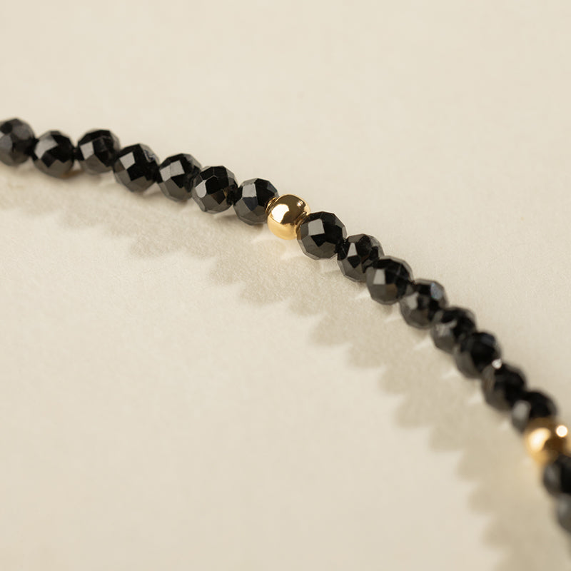 Close-up of faceted black spinel beads with gold vermeil accent on freshwater pearl bracelet