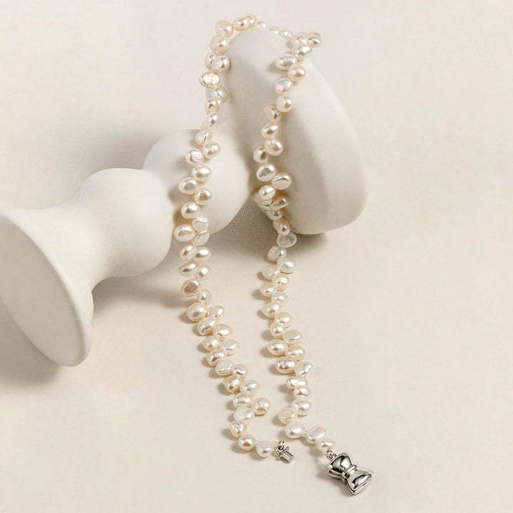 Freshwater pearl strand necklace with butterfly clasp draped on white sculptural display stand