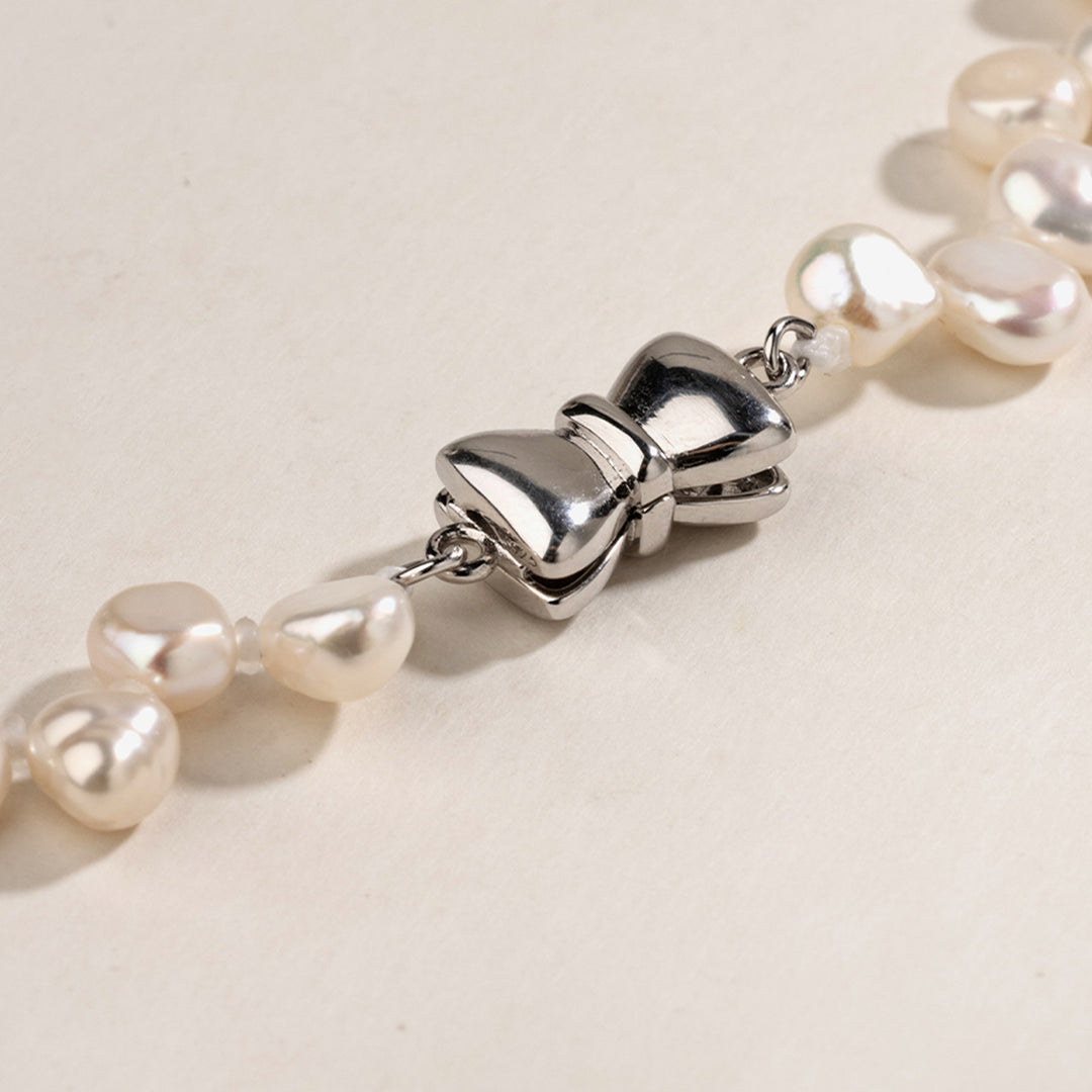 Close-up of butterfly-shaped sterling silver clasp on freshwater pearl strand necklace