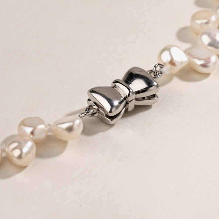 Close-up of butterfly-shaped sterling silver clasp on freshwater pearl strand necklace