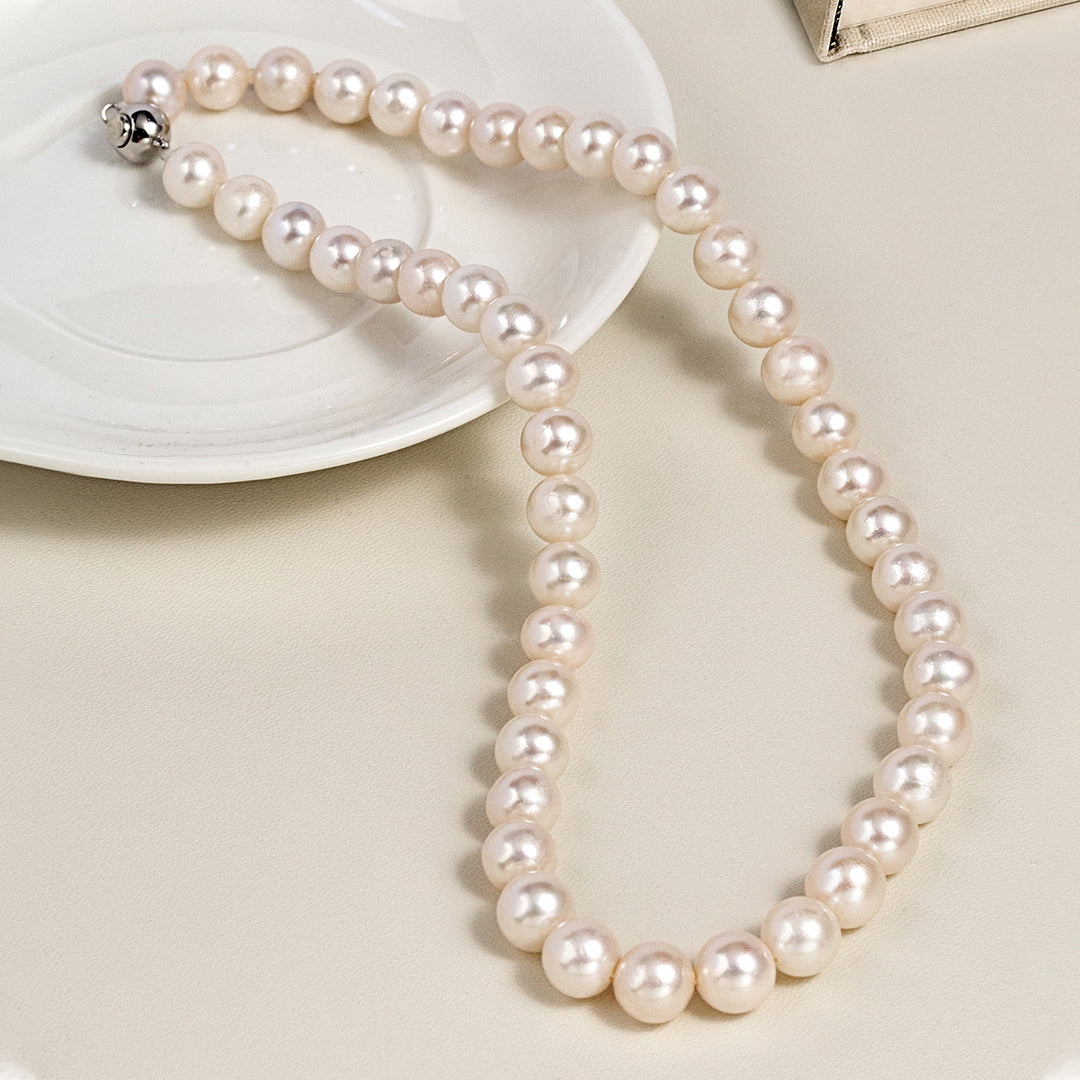 925 sterling silver round freshwater pearl strand necklace laid on white ceramic plate, lifestyle flatlay