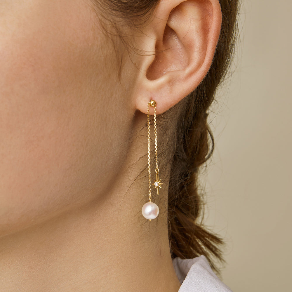 Model wearing gold plating freshwater pearl north star chain drop earrings, side ear close-up