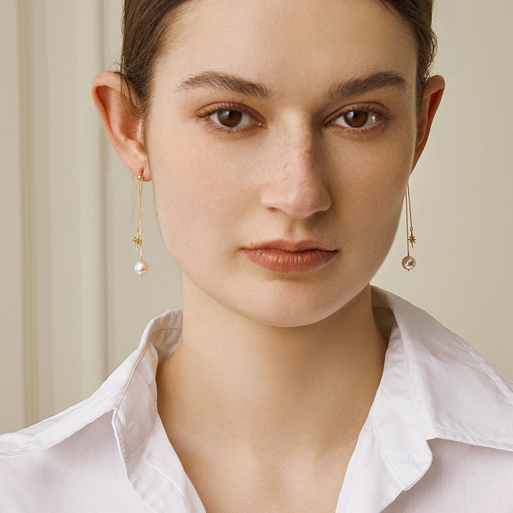 Front on-body view of gold plating north star pearl chain drop earrings on model