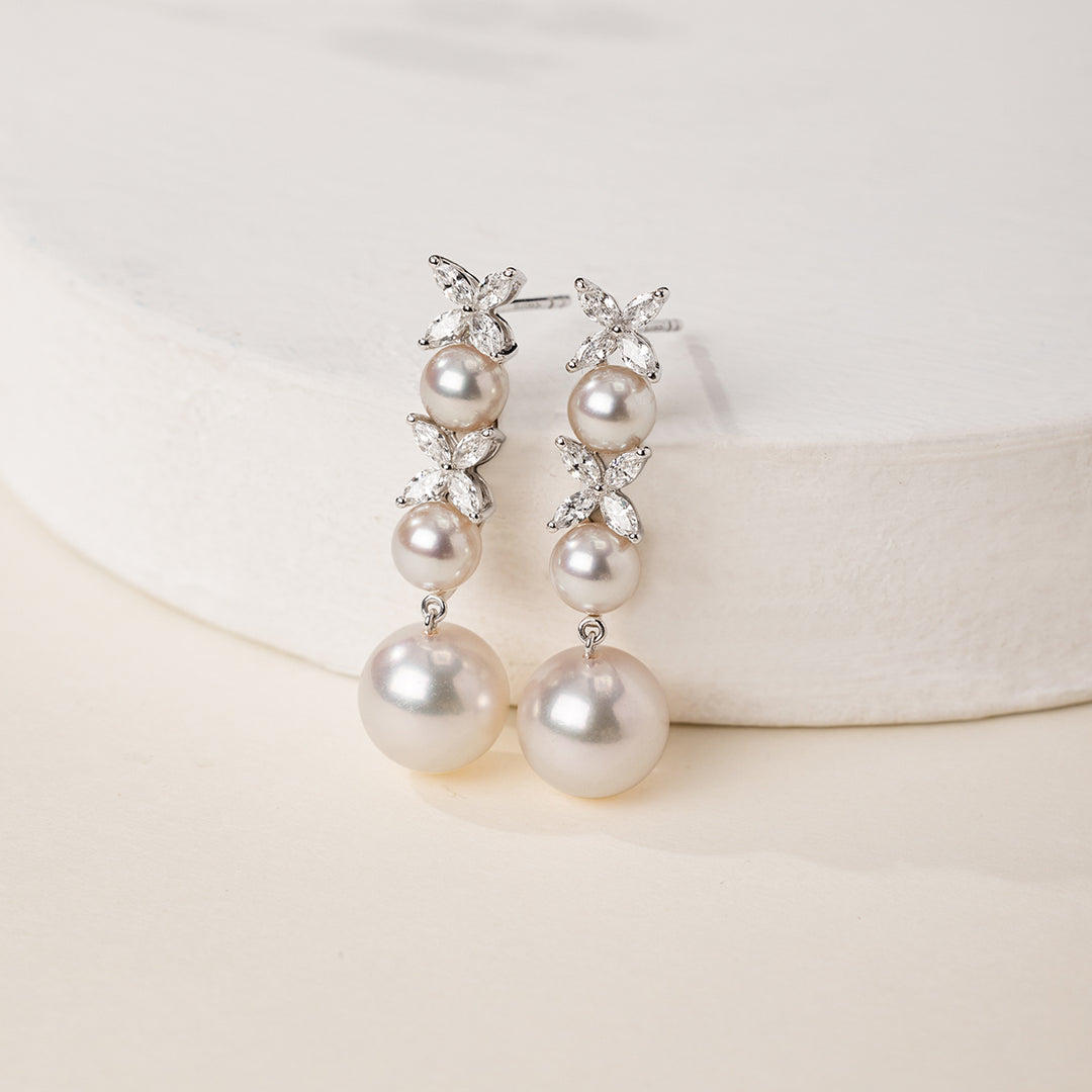 Graduated freshwater pearl drop earrings with marquise lab-grown diamond clusters on white ceramic stand, lifestyle shot