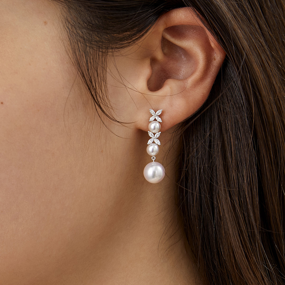 Model wearing graduated freshwater pearl and lab-grown diamond drop earrings in 925 sterling silver, side ear close-up