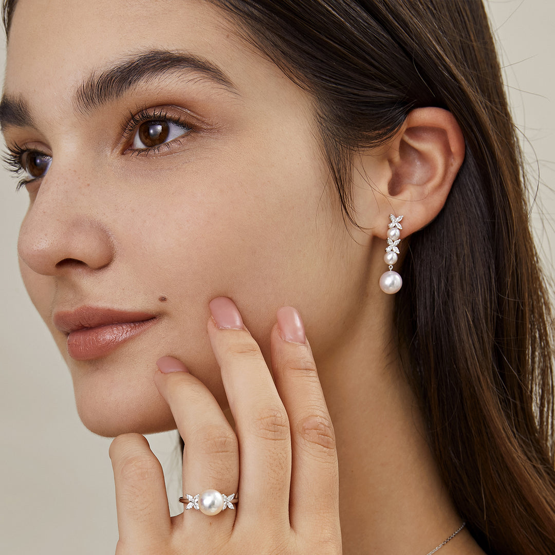 Front face on-body view of model wearing 925 sterling silver graduated pearl diamond drop earrings with matching ring