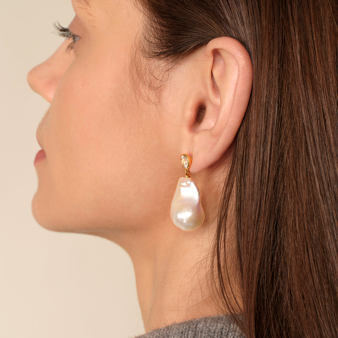 Side profile of model wearing gold-plated baroque pearl necklace with CZ chain, showing pearl drop