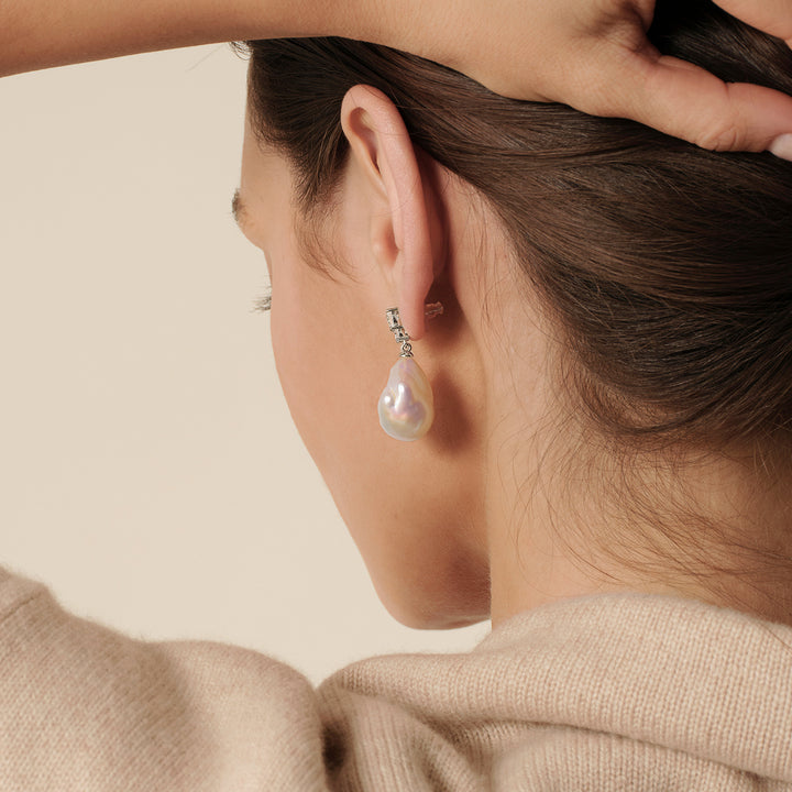 Back view of model wearing 925 sterling silver baroque iridescent freshwater pearl drop earrings, hair up