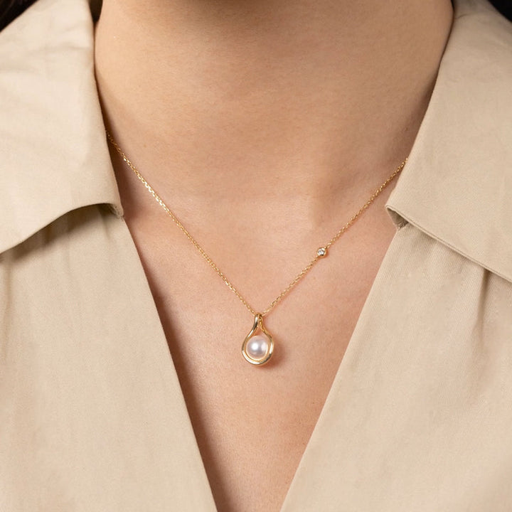 Model wearing freshwater pearl gold vermeil teardrop pendant necklace, styled with neutral collar