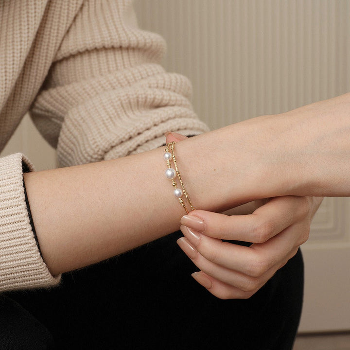 Woman wearing a gold vermeil freshwater pearl stretch bracelet on her wrist
