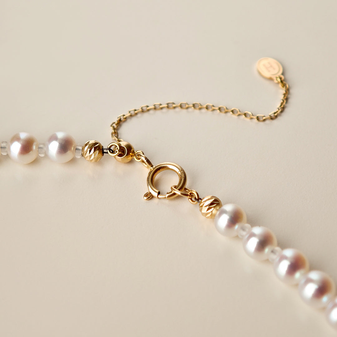 Detail of spring ring clasp, gold bead accents, adjustable extender and HELAS round H logo tag on Aurora freshwater pearl necklace