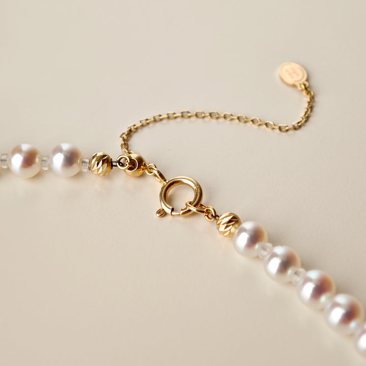 Detail of spring ring clasp, gold bead accents, adjustable extender and HELAS round H logo tag on Aurora freshwater pearl necklace