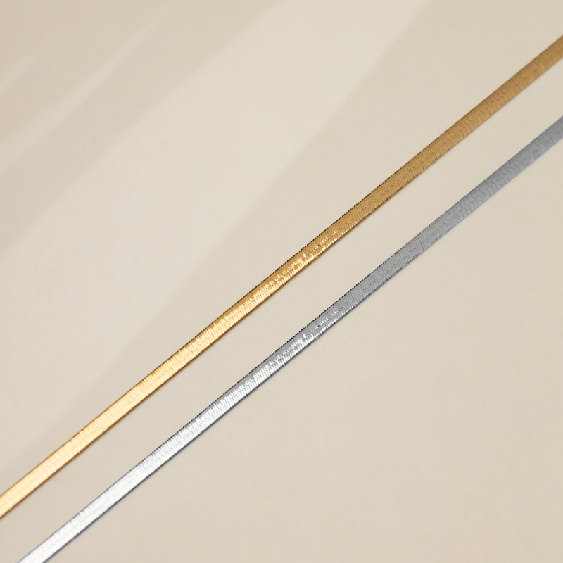 18K solid gold herringbone necklace from Fine Line Collection, showcasing a sleek, polished chain design on a neutral background.