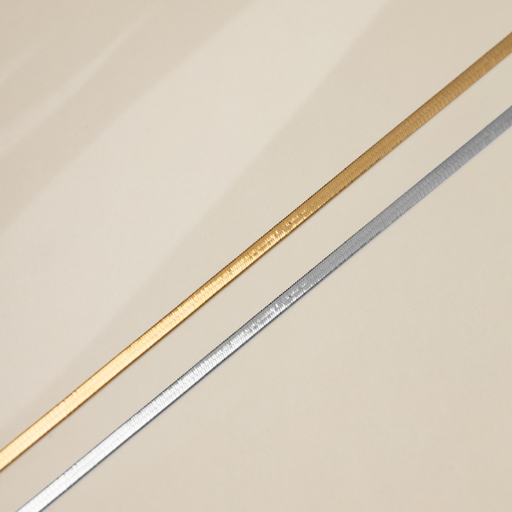 18K solid gold herringbone necklace from Fine Line Collection, showcasing a sleek, polished chain design on a neutral background.