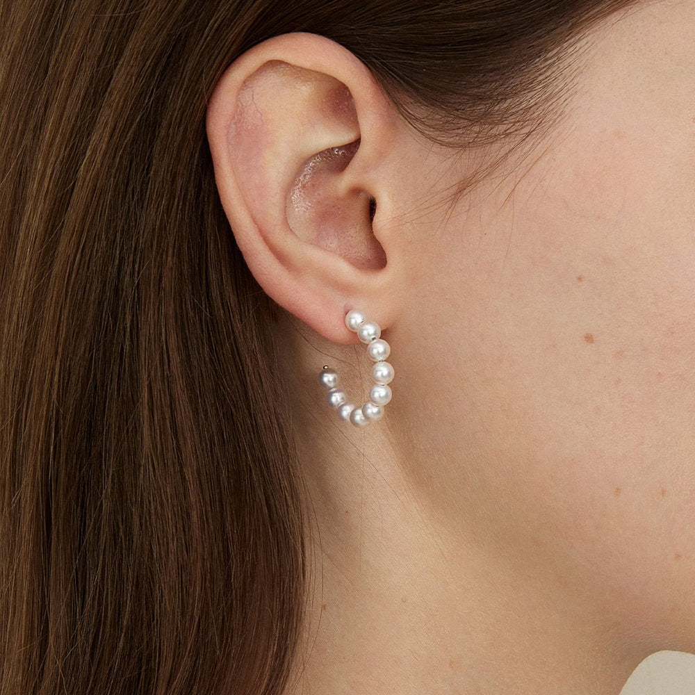Close-up of a woman wearing a gold vermeil freshwater pearl circle earring on her ear