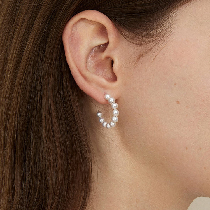Close-up of a woman wearing a gold vermeil freshwater pearl circle earring on her ear