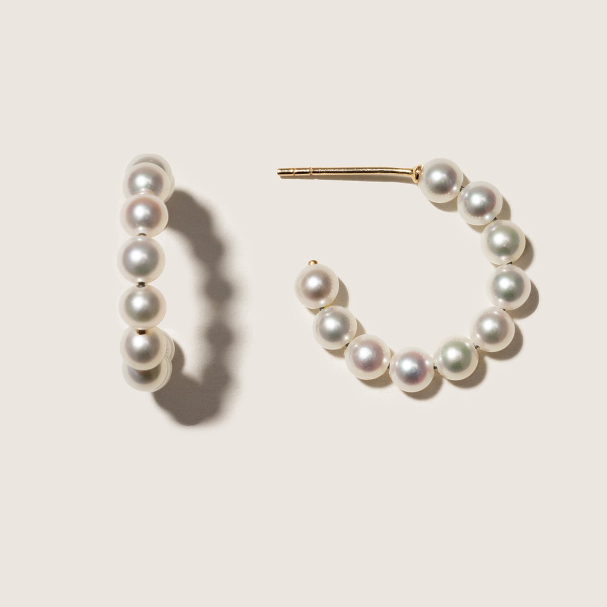 Gold vermeil freshwater pearl circle hoop earrings, pair on a neutral surface