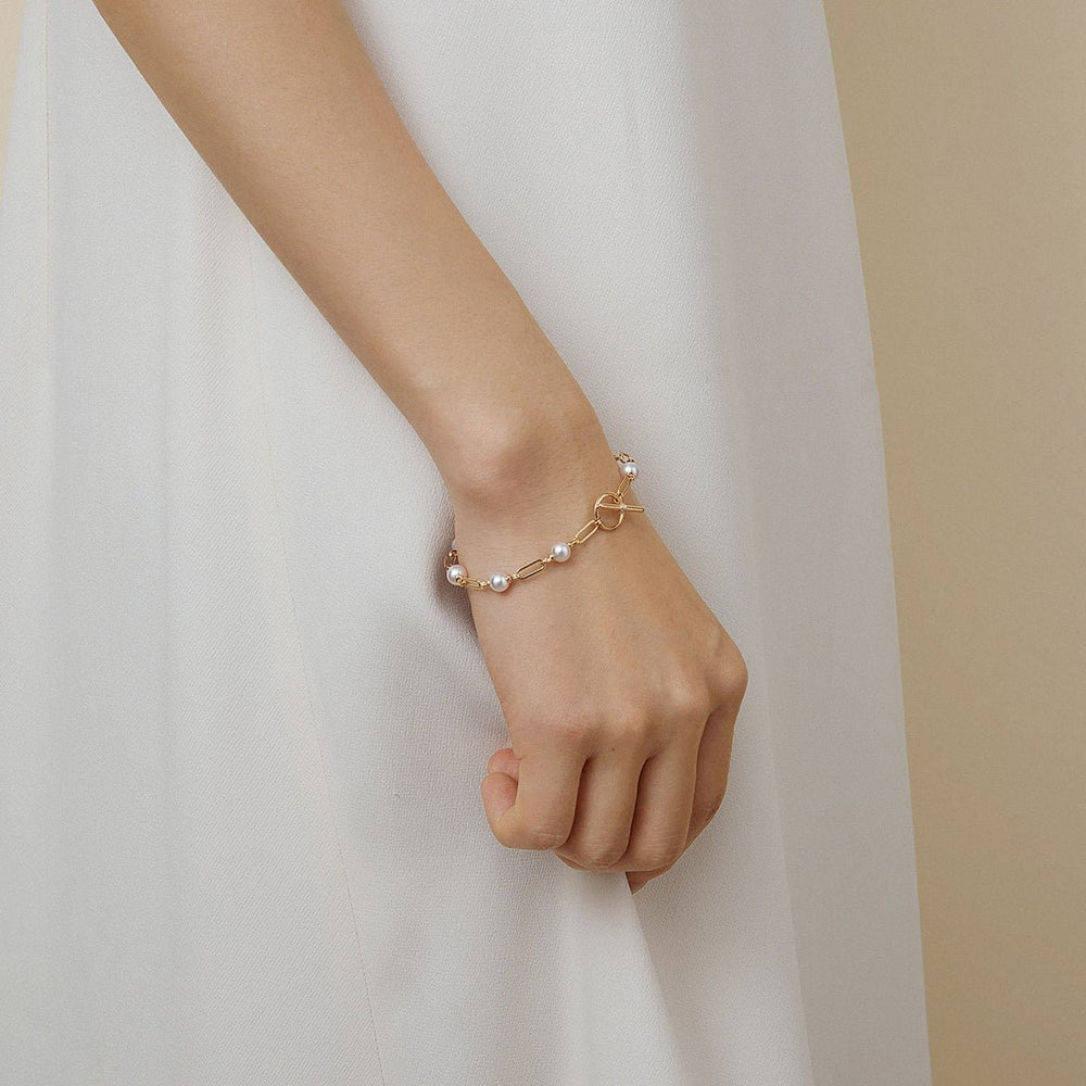 Model wearing freshwater pearl gold vermeil diamond toggle chain bracelet in 925 sterling silver, styled with white dress