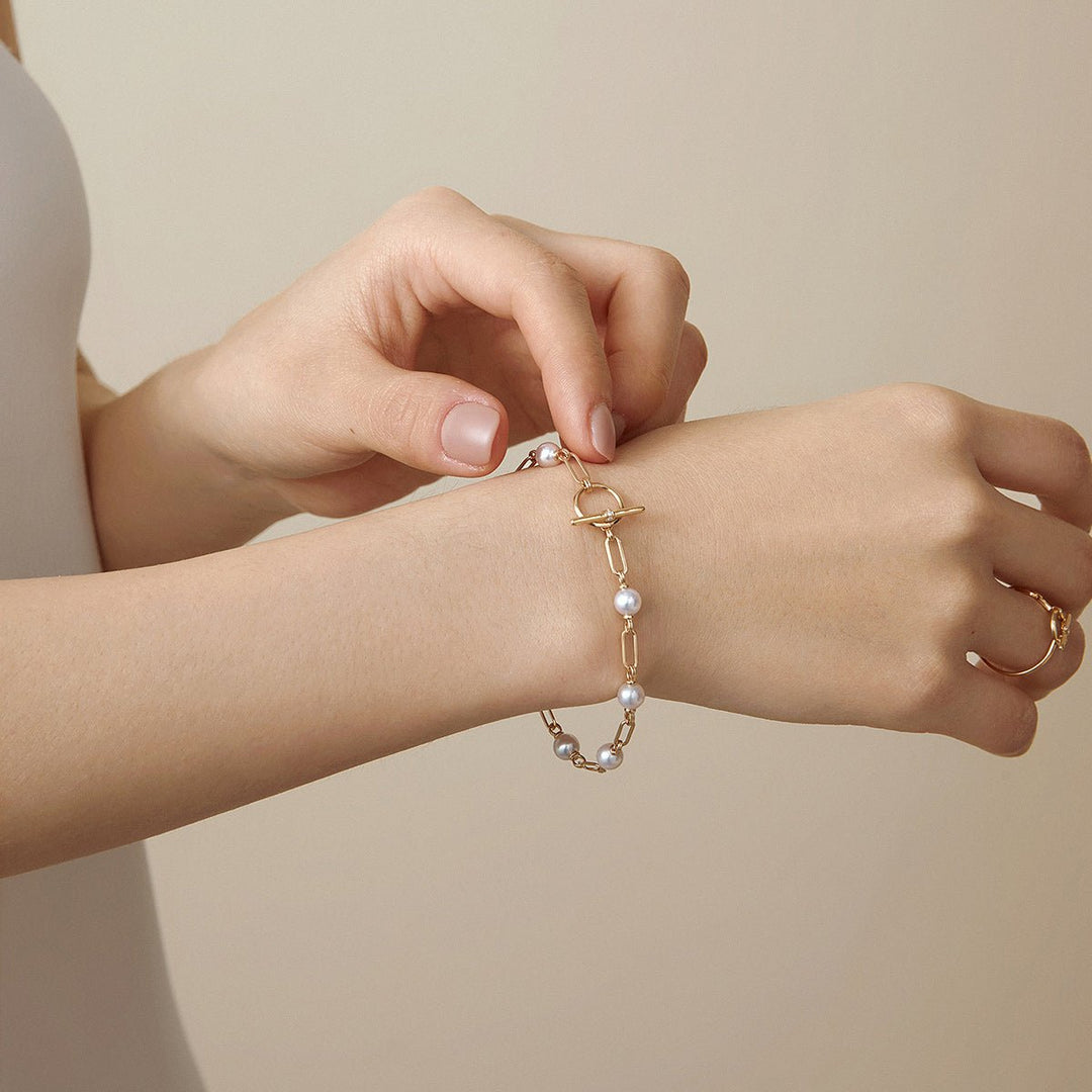 Model fastening gold vermeil pearl chain bracelet OT toggle clasp, styled with matching ring in 925 sterling silver