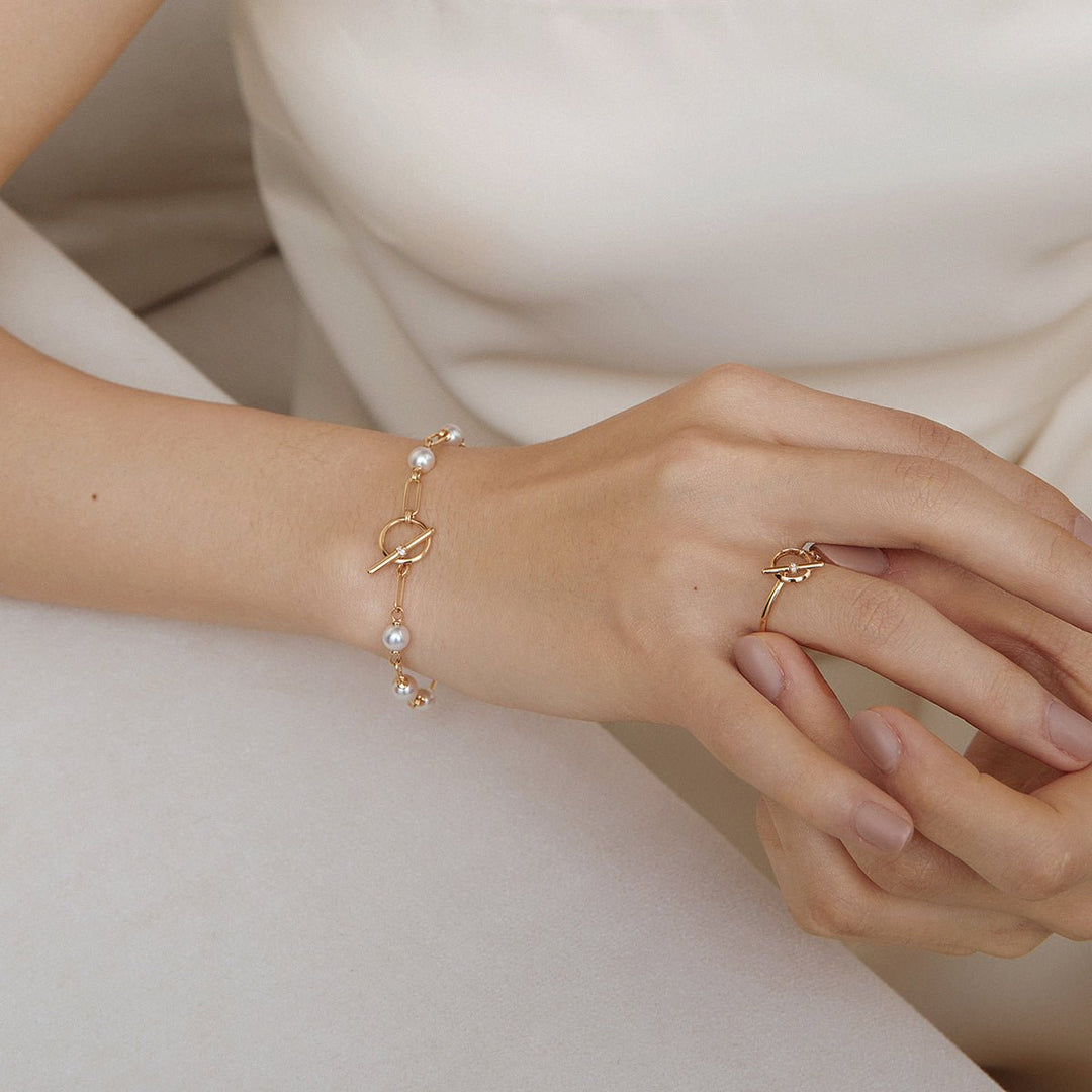 Model with hands overlapping showing AAAAA freshwater pearl gold vermeil toggle bracelet and coordinating ring in 925 sterling silver