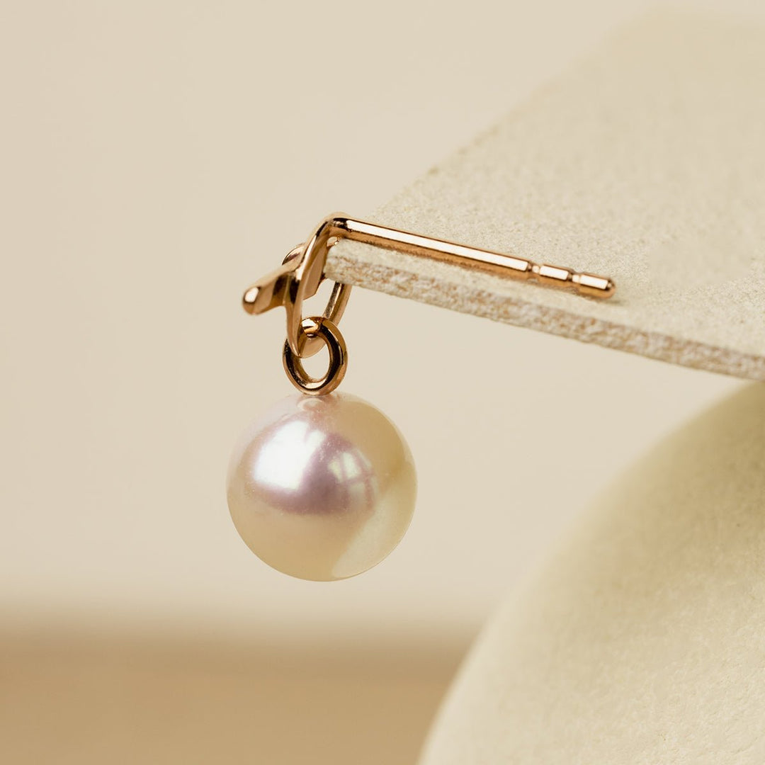 Close-up of freshwater pearl hanging from rose gold vermeil parallel clasp earring, pearl drop detail