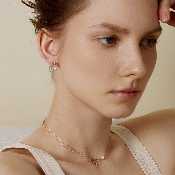 Model wearing freshwater pearl rose gold vermeil parallel clasp earrings with matching necklace, side profile
