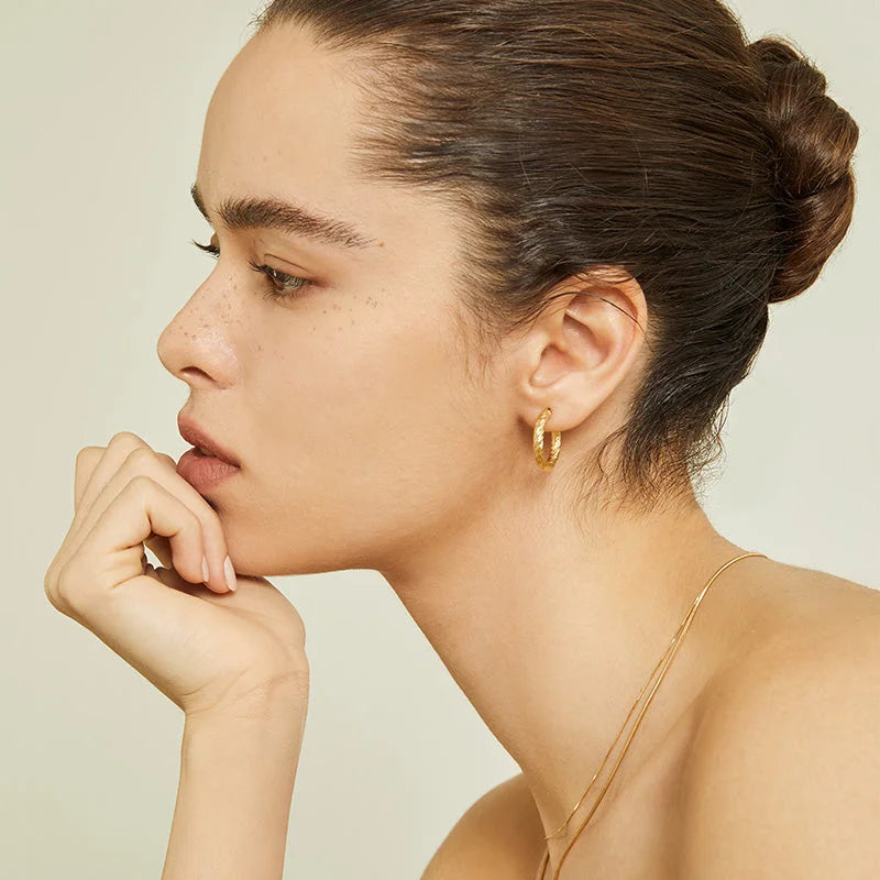 Woman wearing a gold vermeil knot-textured hoop earring