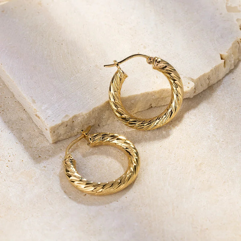 Gold vermeil knot-textured hoop earrings on a stone surface