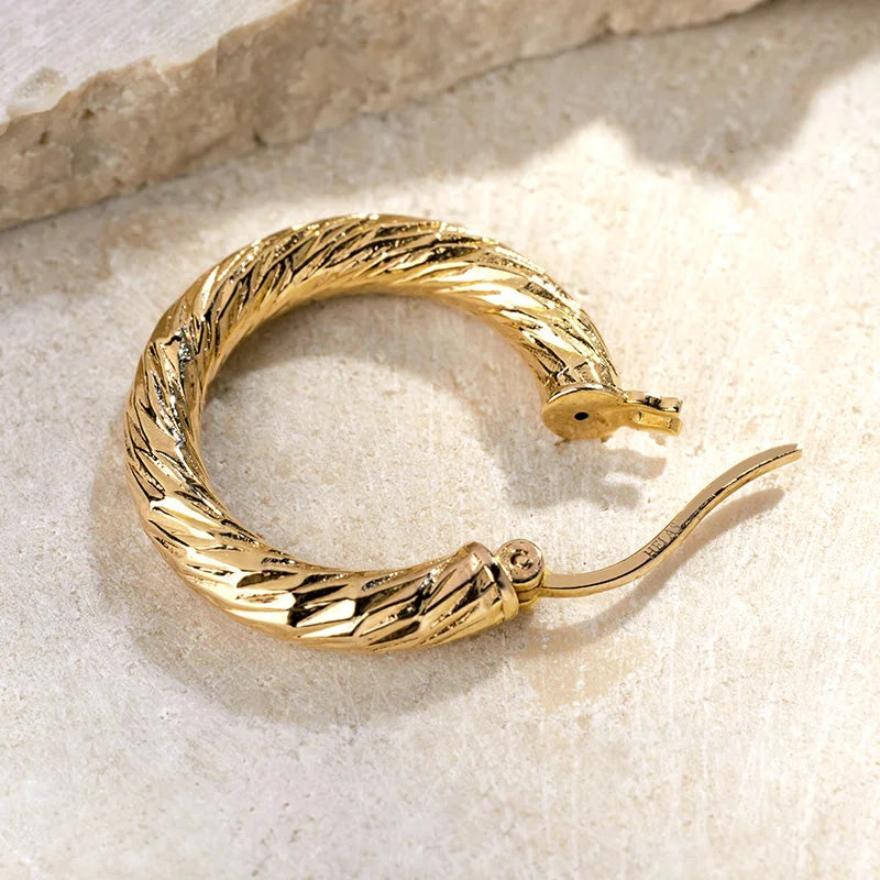 Close-up of a gold vermeil knot-textured hoop earring, twisted rope texture and hinge clasp