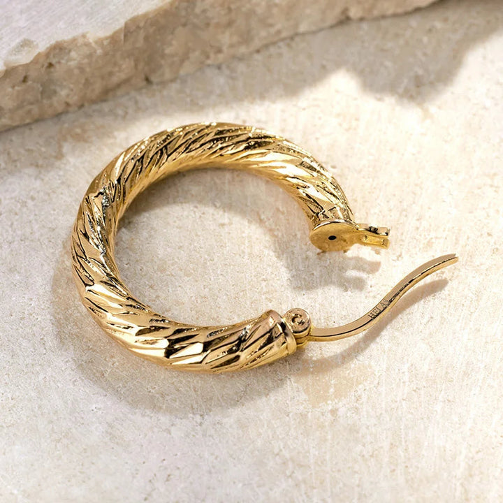Close-up of a gold vermeil knot-textured hoop earring, twisted rope texture and hinge clasp