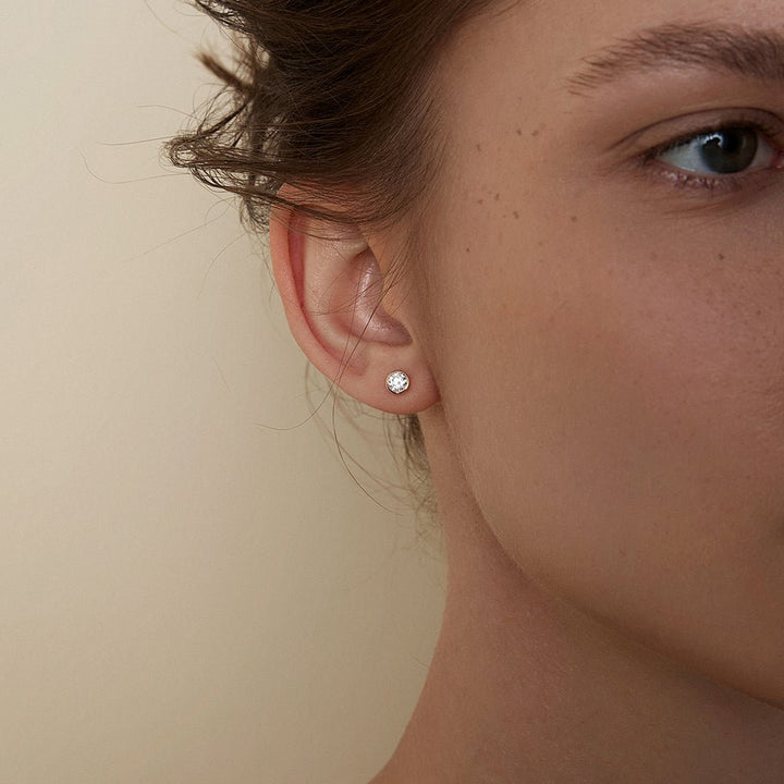 Model wearing lab-grown diamond gold vermeil bezel stud earring, close-up side profile