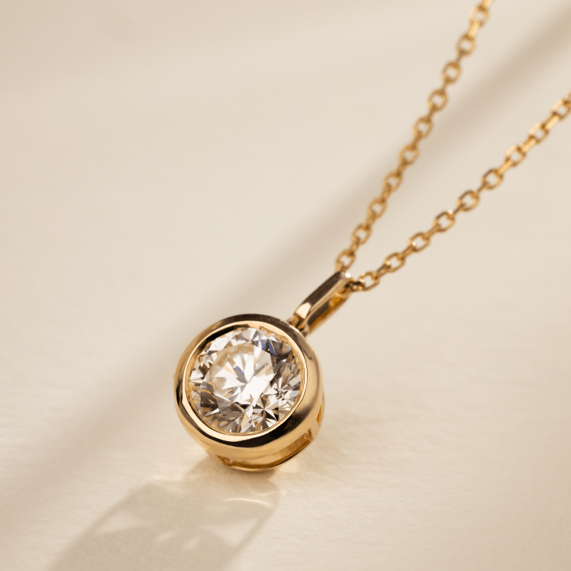 Close-up of round brilliant lab-grown diamond in gold vermeil bezel pendant, side light