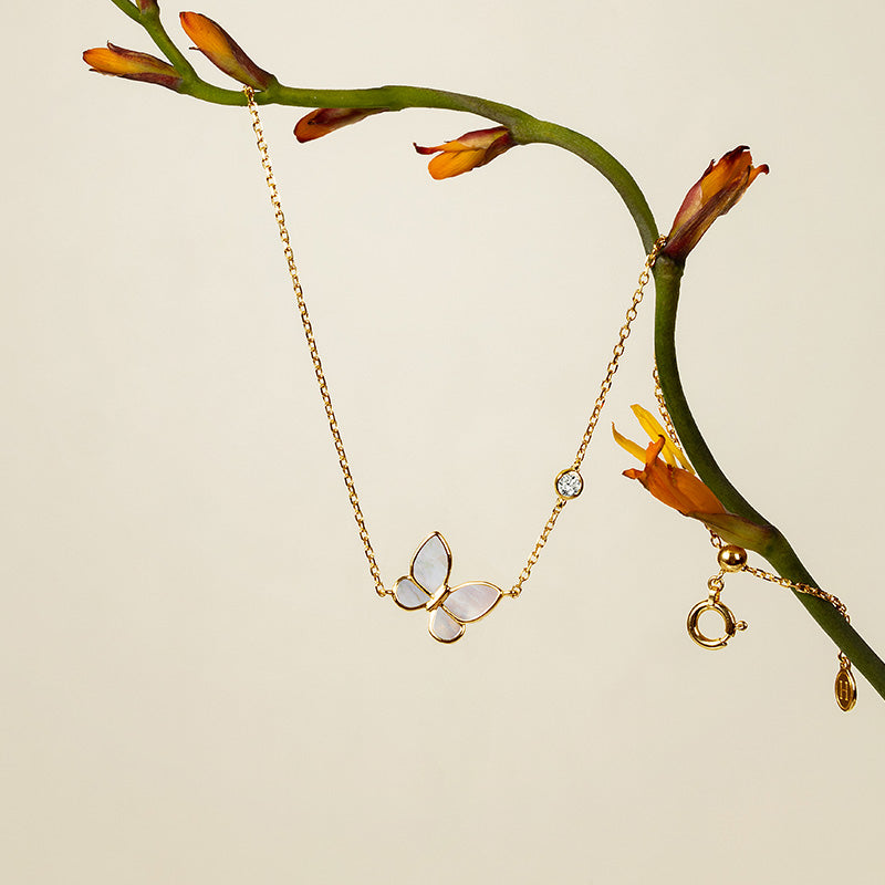 Mother-of-pearl butterfly charm bracelet with lab-grown diamond accent, hanging on botanical branch, gold vermeil sterling silver