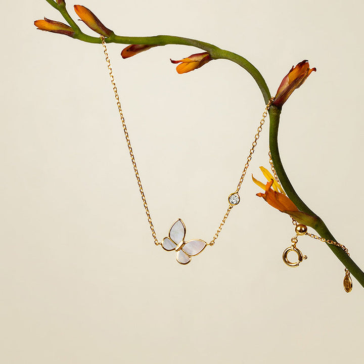 Mother-of-pearl butterfly charm bracelet with lab-grown diamond accent, hanging on botanical branch, gold vermeil sterling silver
