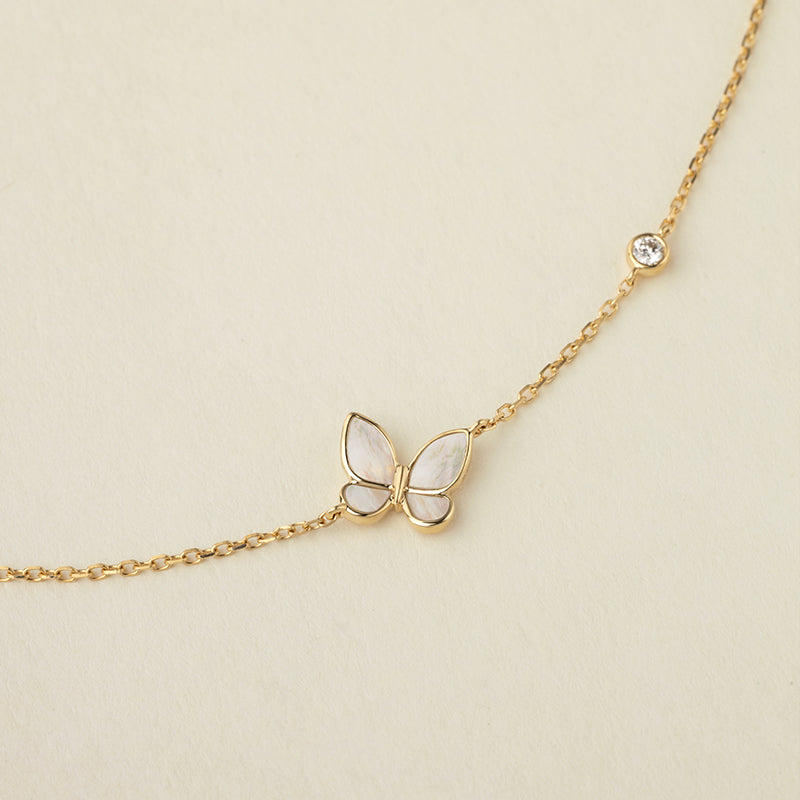 Close-up detail of mother-of-pearl butterfly pendant and bezel-set lab-grown diamond on gold vermeil sterling silver bracelet