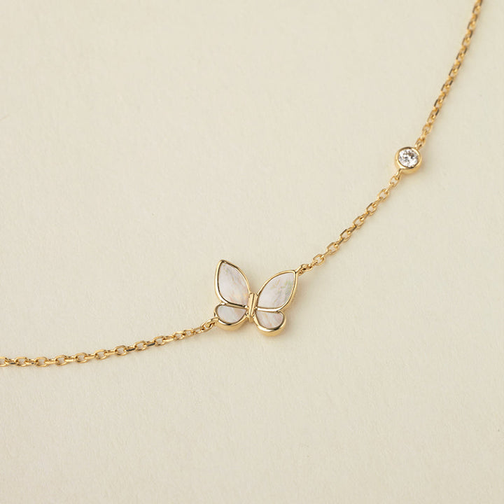 Close-up detail of mother-of-pearl butterfly pendant and bezel-set lab-grown diamond on gold vermeil sterling silver bracelet