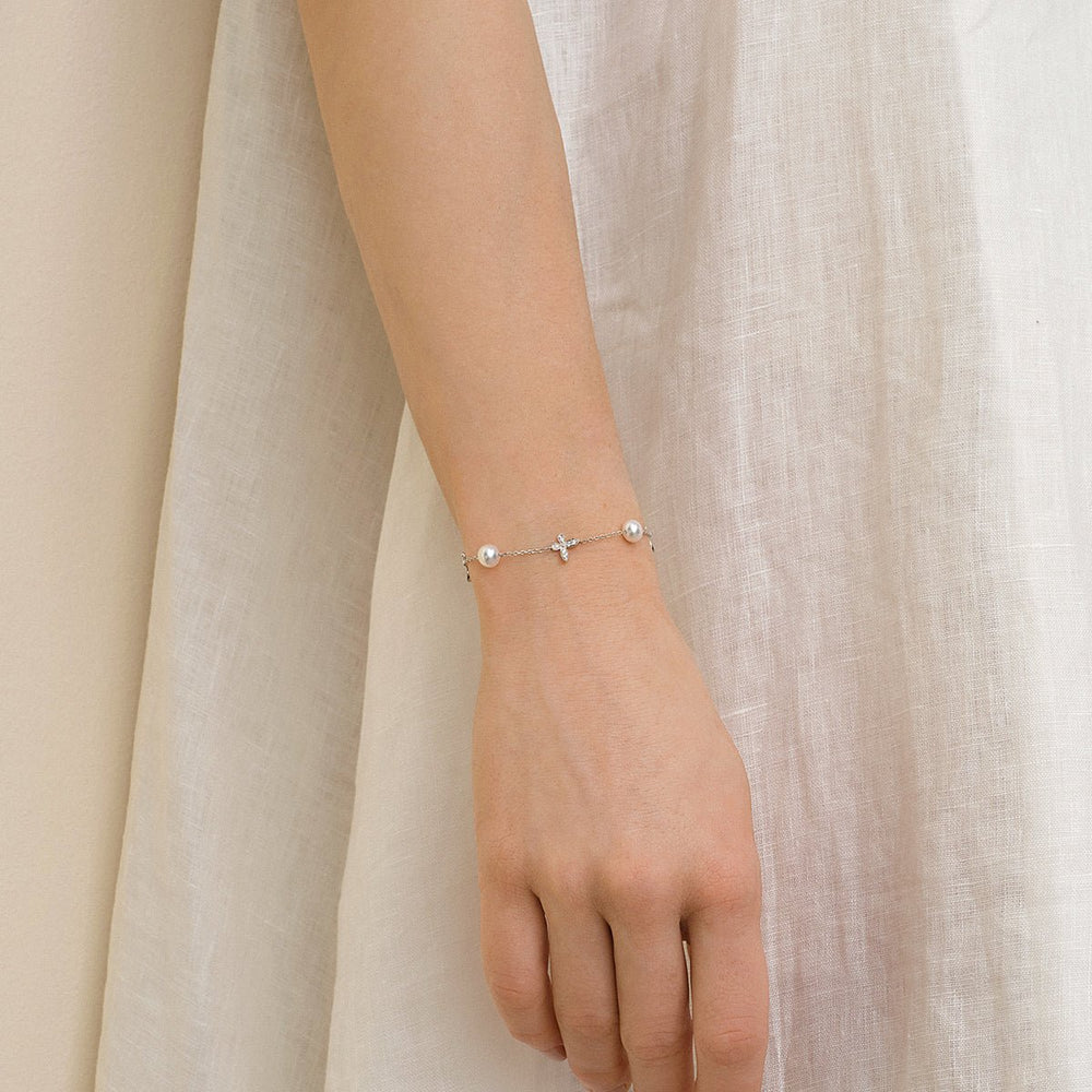 Model wearing freshwater pearl and lab-grown diamond butterfly bracelet in 925 sterling silver, styled with white dress