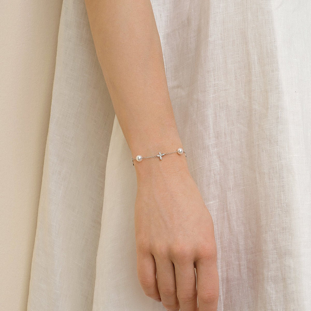 Model wearing freshwater pearl and lab-grown diamond butterfly bracelet in 925 sterling silver, styled with white dress