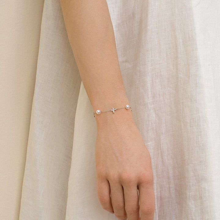 Model wearing freshwater pearl and lab-grown diamond butterfly bracelet in 925 sterling silver, styled with white dress