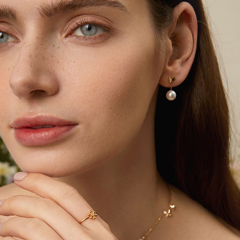 Model wearing freshwater pearl gold vermeil butterfly drop earring in 925 sterling silver, face close-up with matching ring and necklace