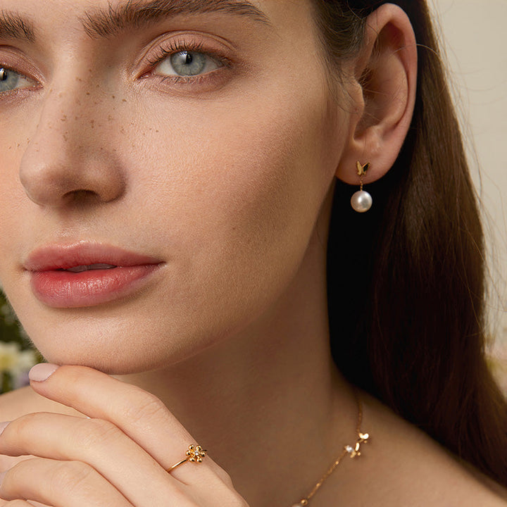 Model wearing freshwater pearl gold vermeil butterfly drop earring in 925 sterling silver, face close-up with matching ring and necklace