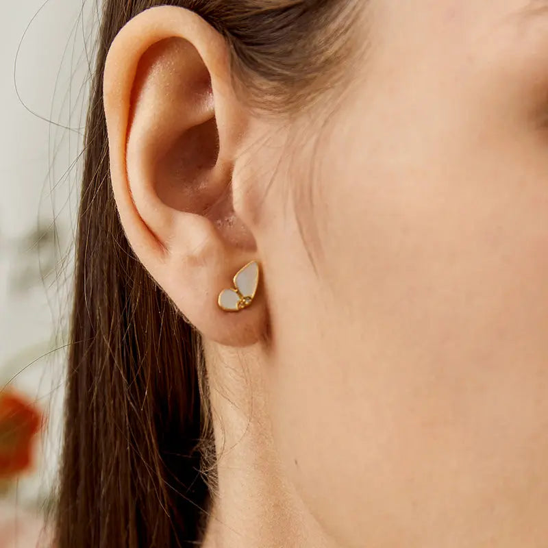 Close-up of mother-of-pearl gold vermeil diamond butterfly stud earring worn on ear