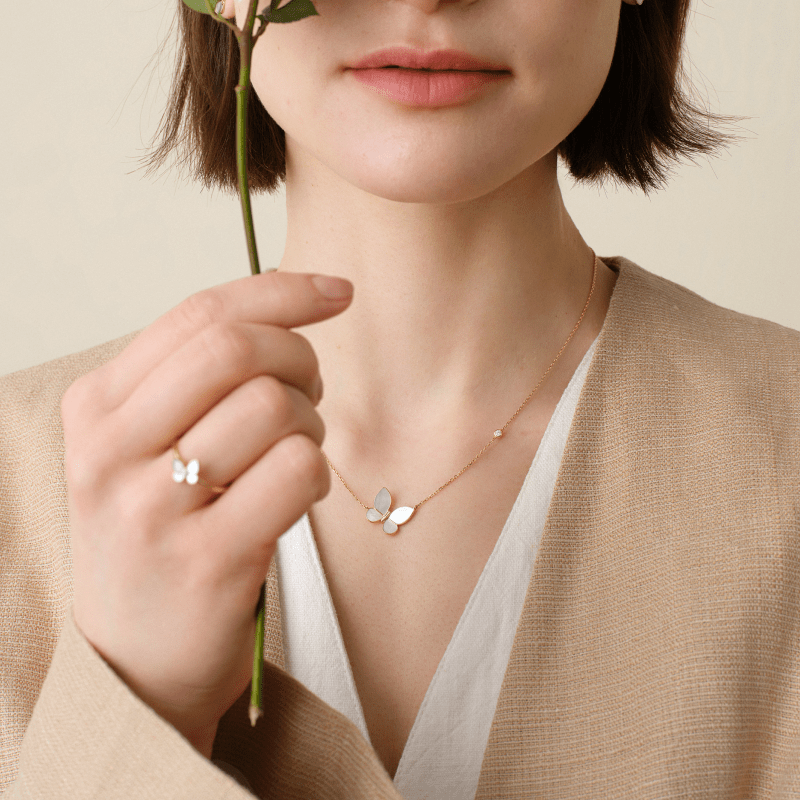 Woman wearing a gold-vermeil sterling silver mother-of-pearl butterfly necklace, with a matching butterfly ring