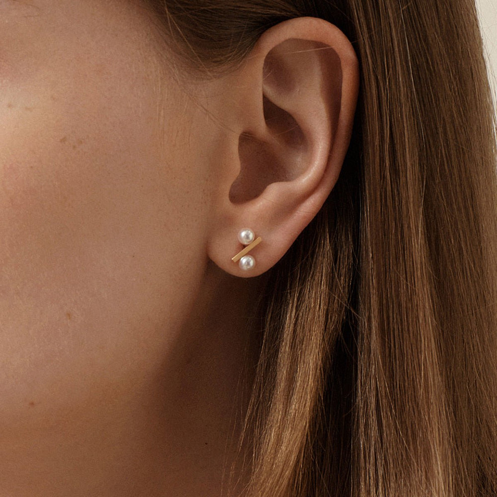 Model wearing freshwater AAAAA pearl gold vermeil percent bar stud earring, close-up side view