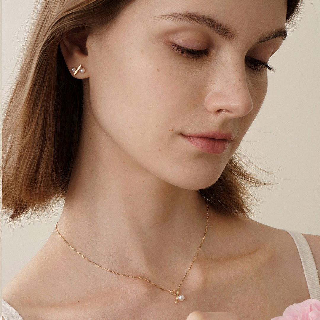Model wearing freshwater pearl gold vermeil percent stud earrings with matching necklace, downward gaze
