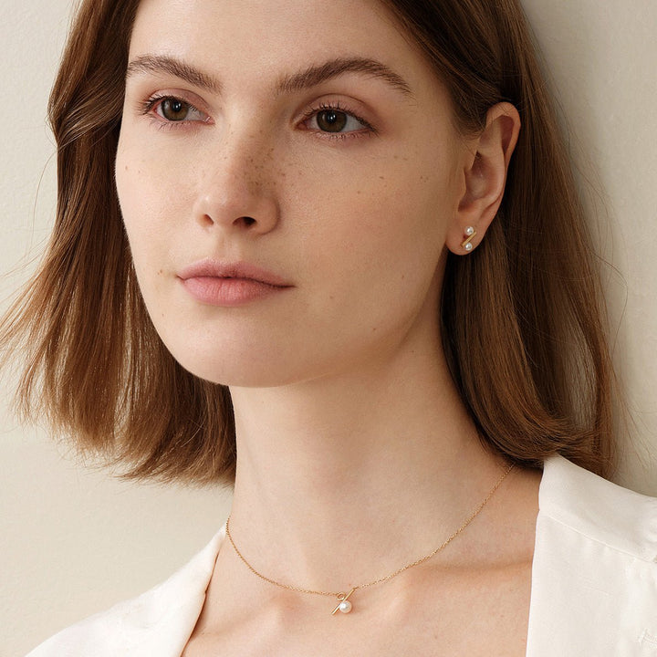 Model wearing freshwater pearl gold vermeil percent stud earrings with matching pearl necklace, front view