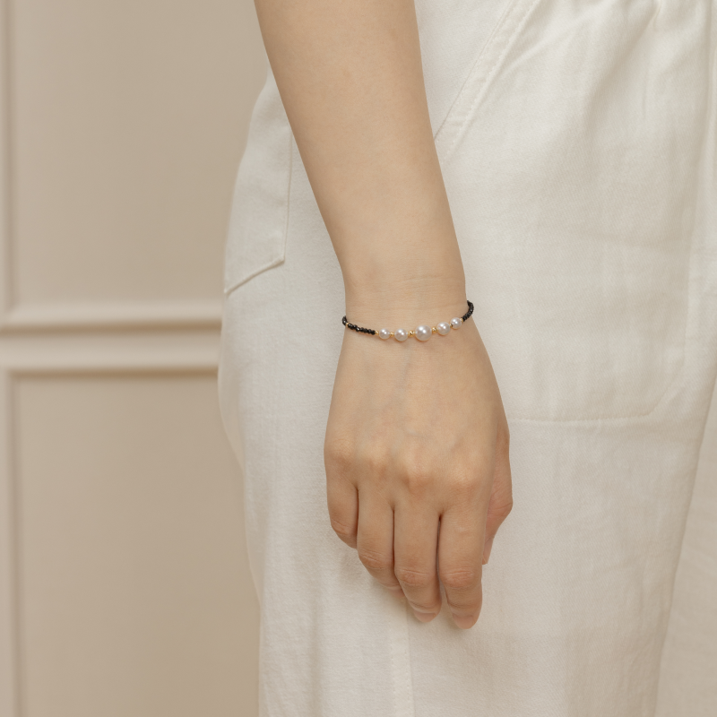 Model wearing freshwater pearl and black spinel gold vermeil smile bracelet, front wrist view