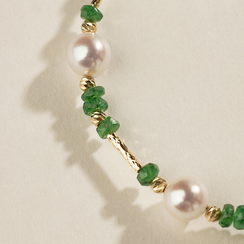Close-up of freshwater pearls, tsavorite garnets, and gold vermeil tube links on baby's breath bracelet